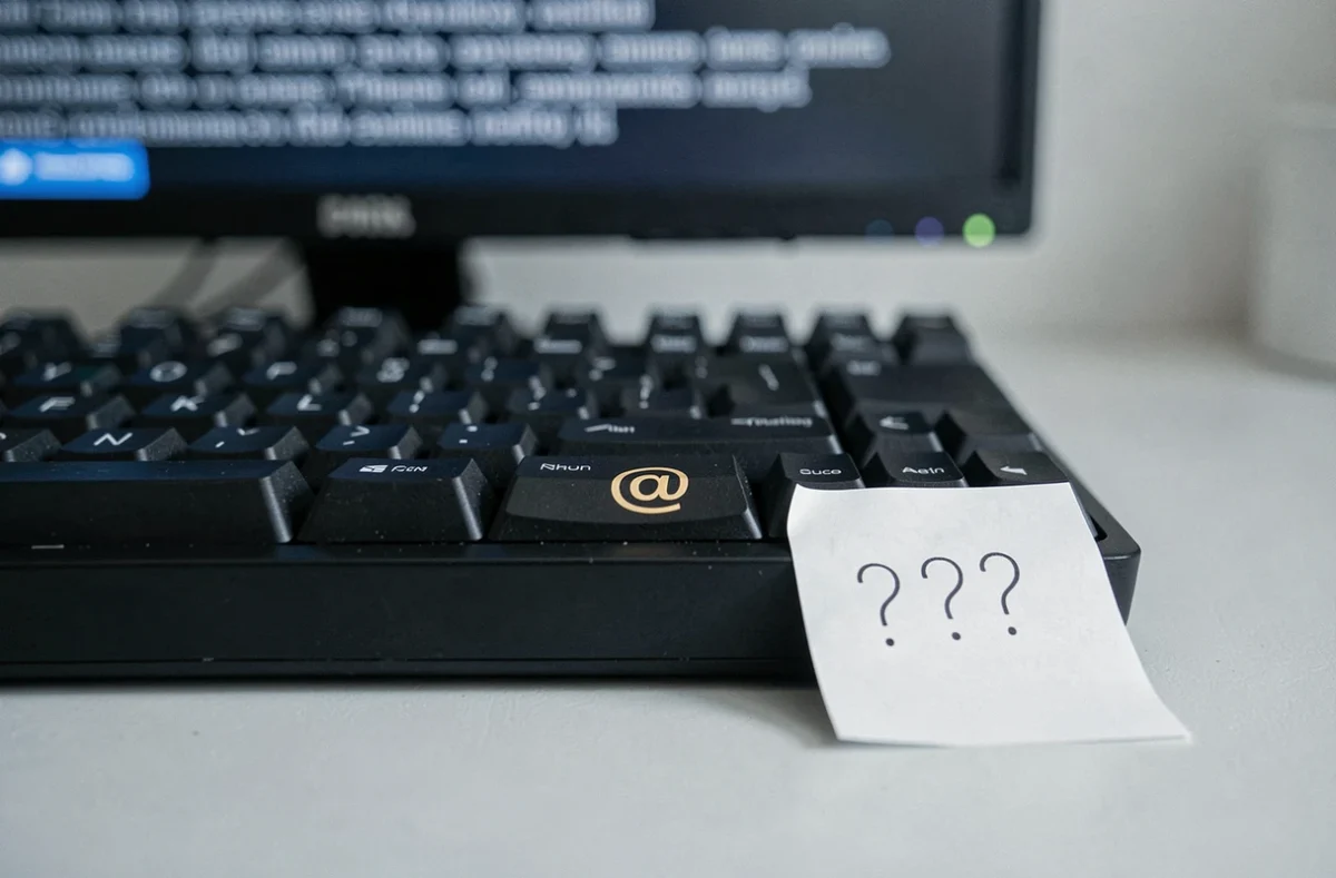 Gros plan sur la touche arobase d'un clavier mécanique avec un pense-bête posé dessus, symbolisant un problème de configuration